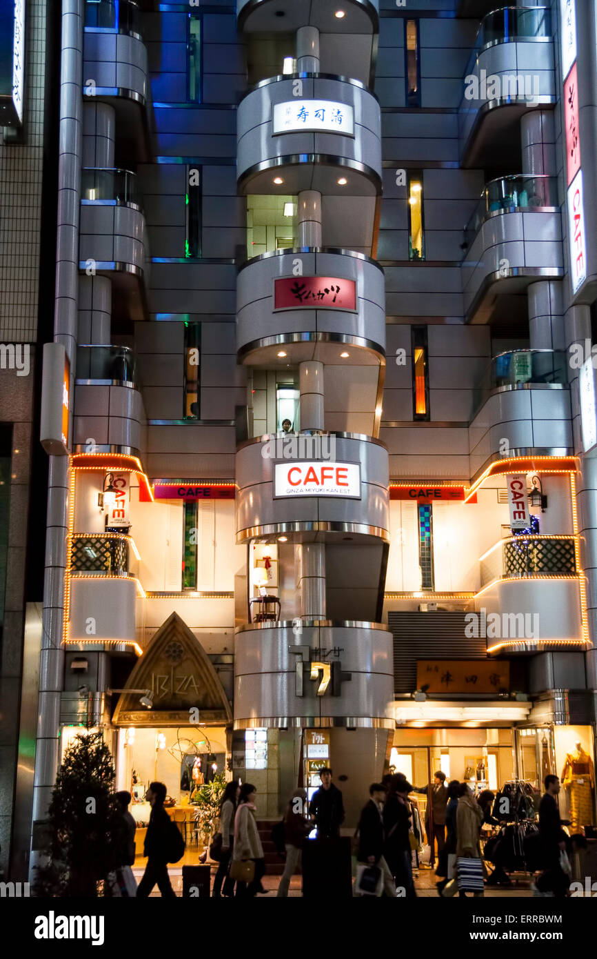 Exterior of the Cafe de Ginza Miyuki-kan in the distinctive W facade shape of the Ginza Act Building in Tokyo at night. People passing by in front. Stock Photo