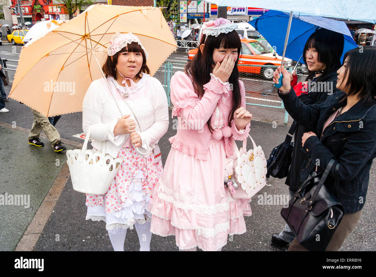 Tokyo, Harajuku. Cosplay. Two Japanese women in Goth 'Sweet Lolita' clothing, taking to two other young women in black goth clothing. Raining. Stock Photo