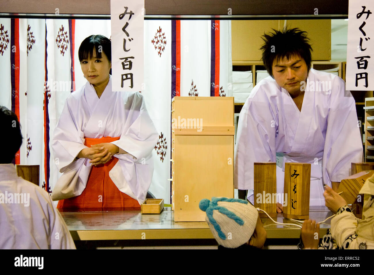 Japanese manned Shinto office counter where people go to buy omamori, paper  fortune slips. Evening on new year's eve. Shrine Maiden and male assistant  Stock Photo - Alamy