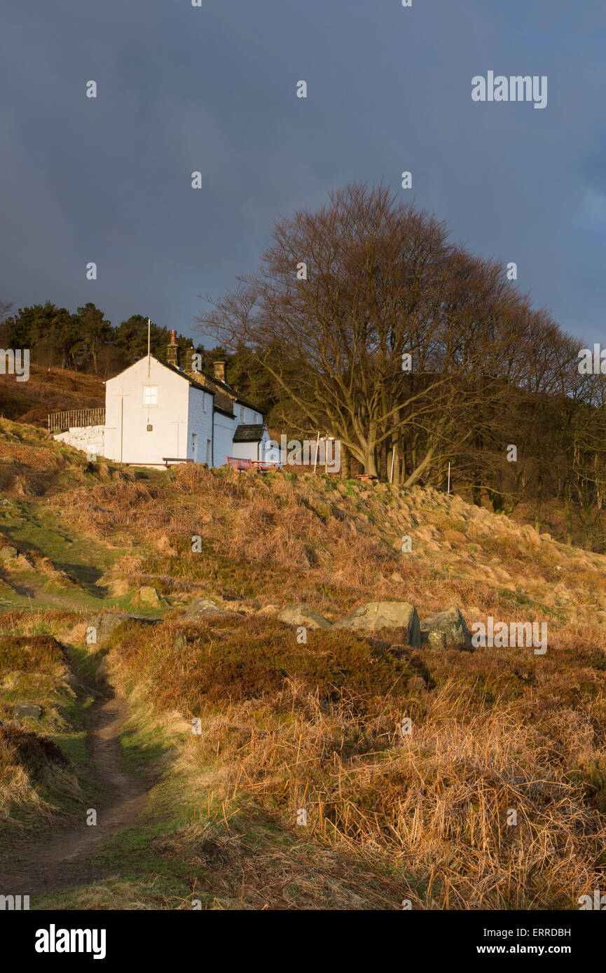 Sunlit under a blue sky, solitary & isolated, White Wells Spa Cottage, is perched high on a hillside slope - Ilkley Moor, West Yorkshire, England, UK. Stock Photo