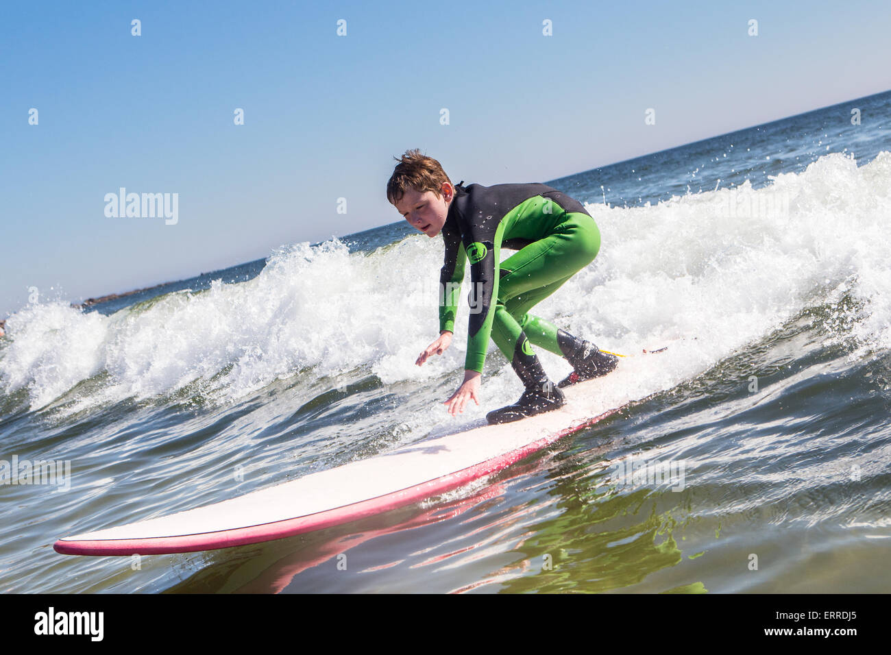 Little boy surfing in green wetsuit Stock Photo