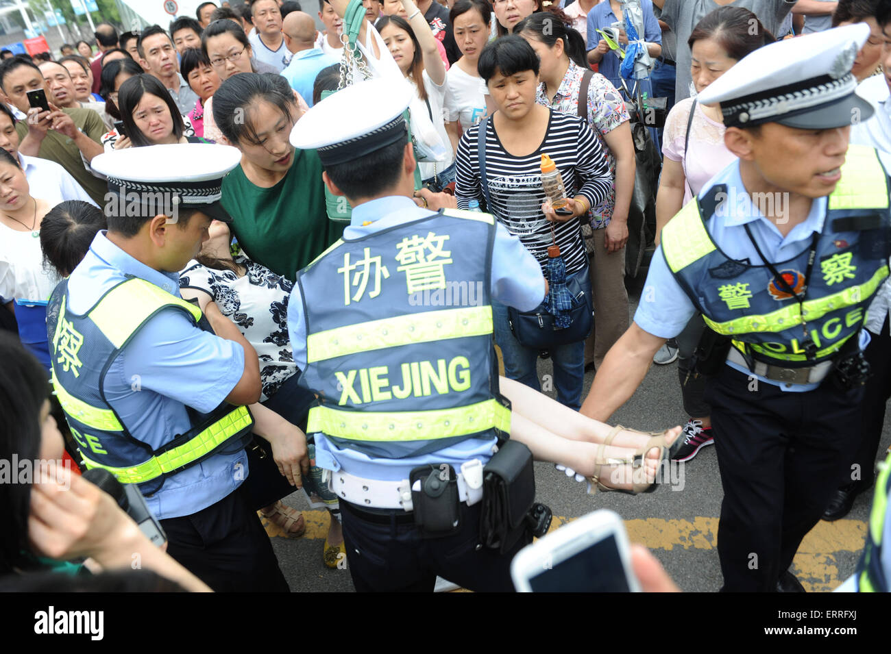 Jiaxing, China. 07th June, 2015. Policemen rescue a woman who fell in a faint when she was  waiting for  to the candidates taking an exam for the national college entrance  at a school in Hefei, Anhui province, east China on 7th  June , 2015. The two-day exams began on Sunday, with 9.42 million students attending to take the exams this year. Credit:  Panda Eye/Alamy Live News Stock Photo