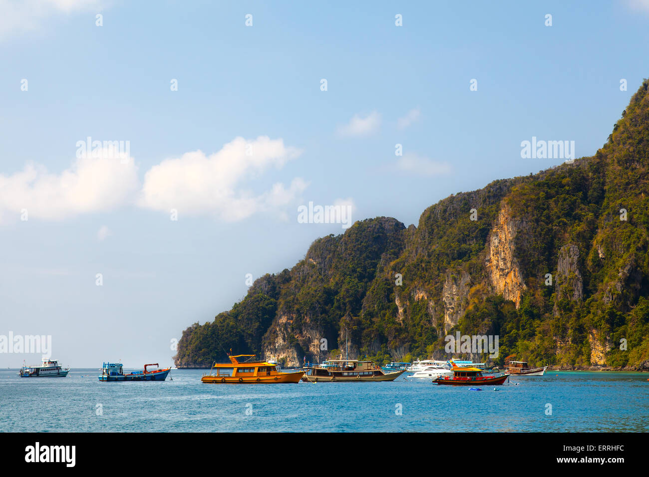 Motor boat with passengers moving on blue tropical Thailand sea near big rocks island Stock Photo