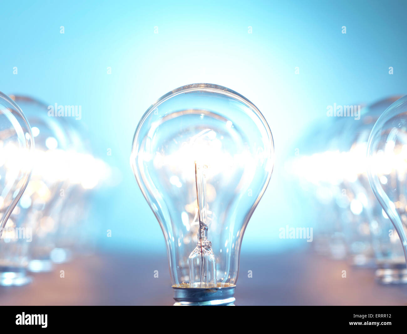 Closeup of lit up incandescent light bulbs on bright blue background. Power consumption concept. Stock Photo