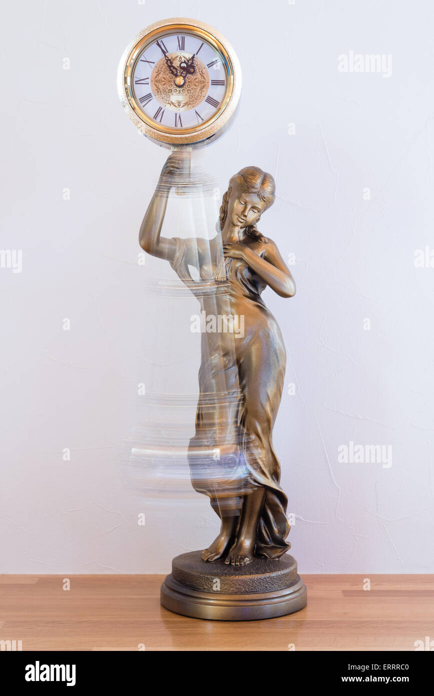 A classic looking bronze statue clock with a swinging pendulum Stock