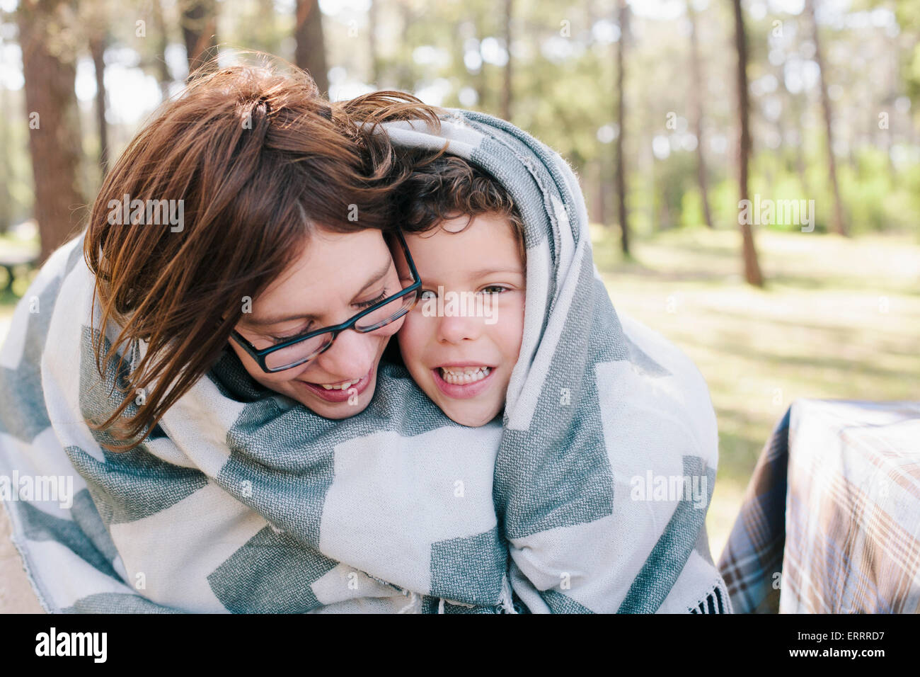 Happy mother and son wrapped in blanket at forest Stock Photo