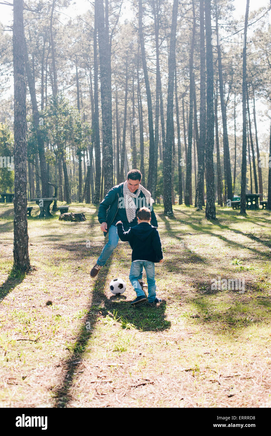 Father and son playing soccer in forest Stock Photo