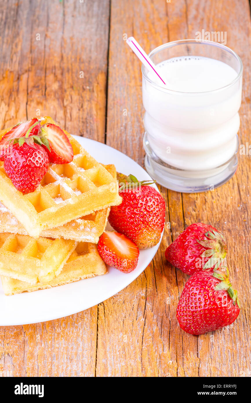 homemade waffles with strawberries maple syrup and glass with milk on wooden background Stock Photo