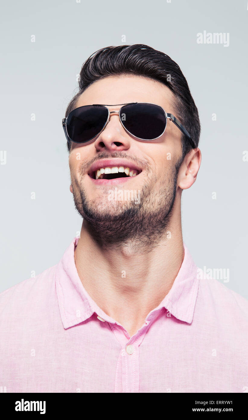 Closeup portrait of a laughing young man in sunglasses over gray ...