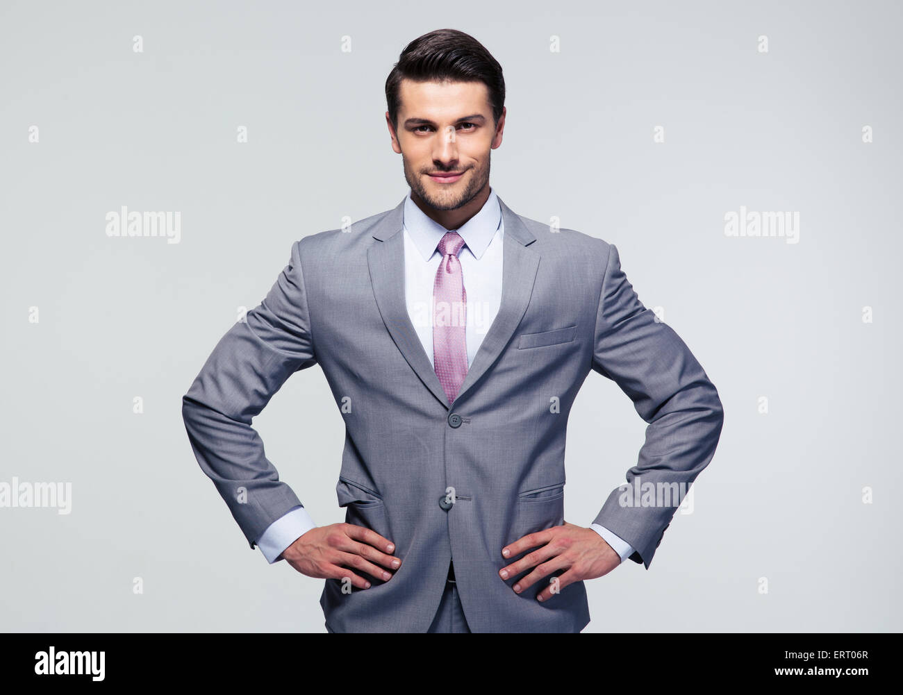 POrtrait of a happy young businessman standing over gray background and looking at camera Stock Photo