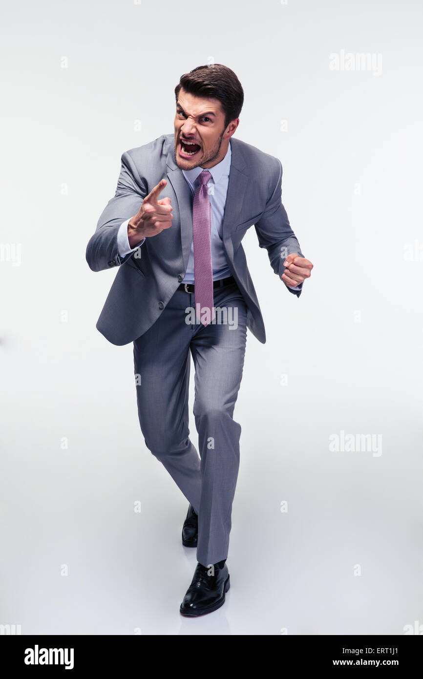 Full length portrait of angry businessman screaming over gray background Stock Photo