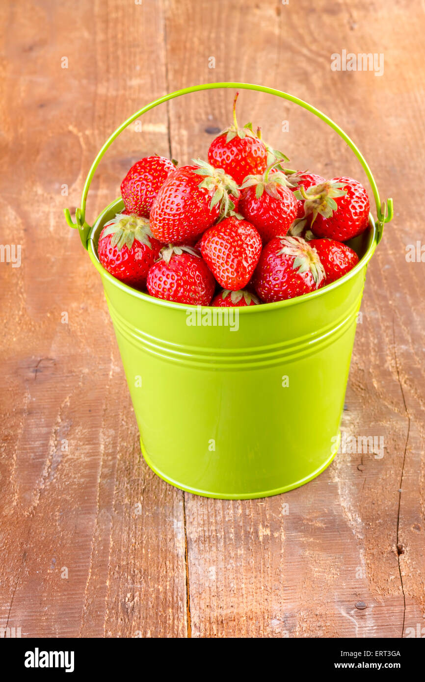 strawberry in a green metal bucket on wooden background Stock Photo