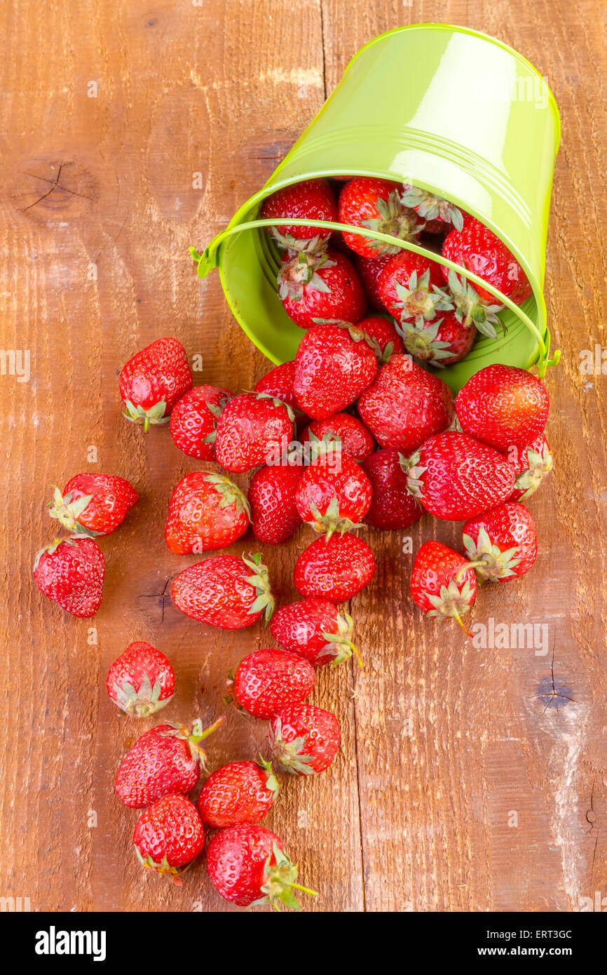 strawberry in a green metal bucket on wooden background Stock Photo