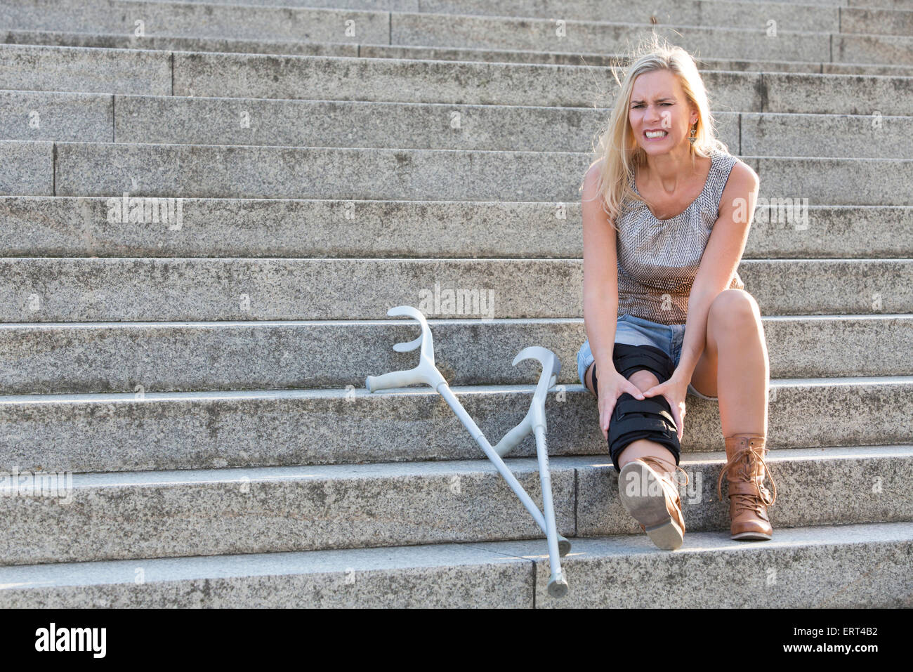 blond woman with crutches sitting on stairs Stock Photo Alamy