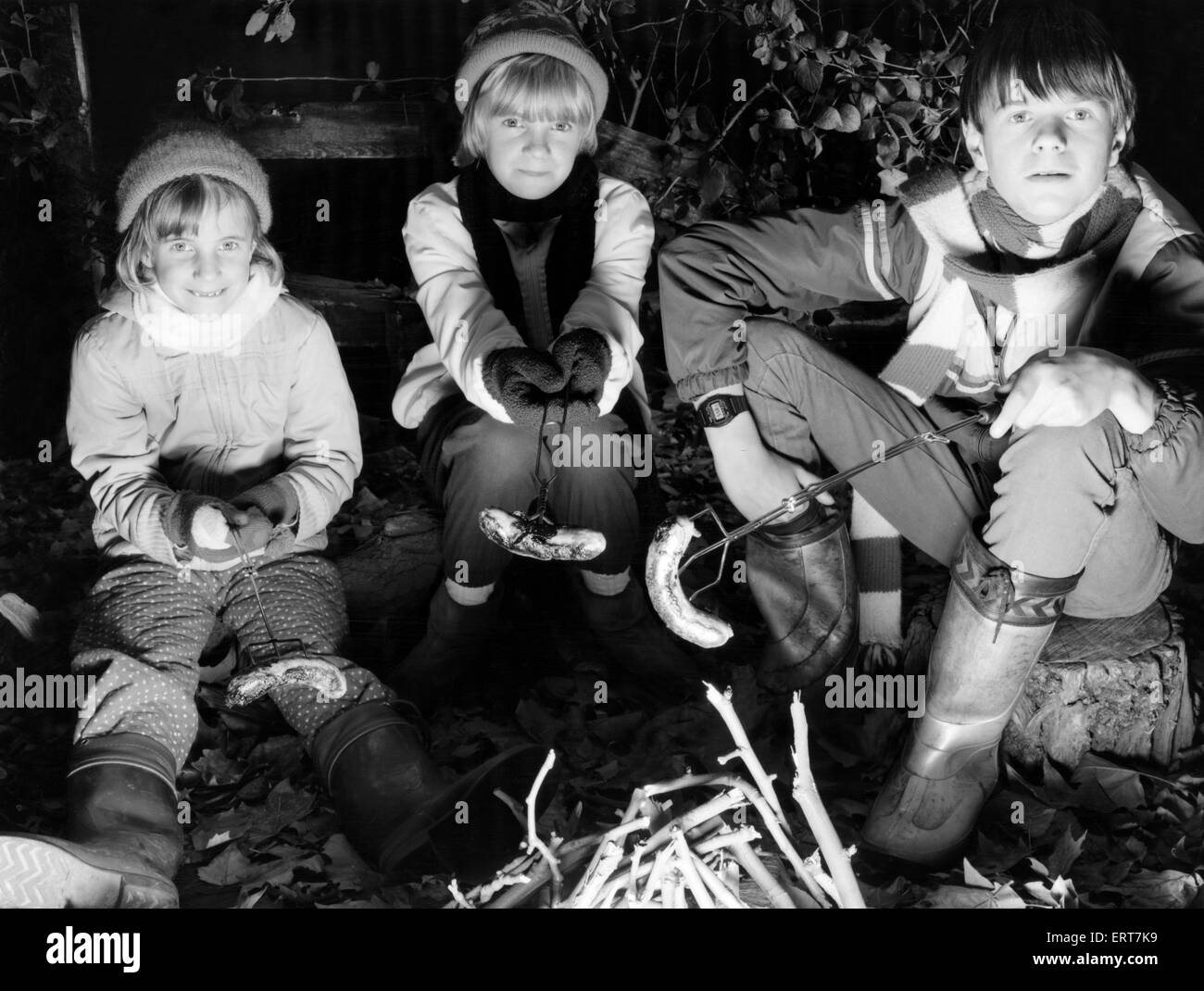 The original bonfire night banger. Children at a private Merseyside bonfire night part cooking sausages over the fire. 5th November 1985 Stock Photo