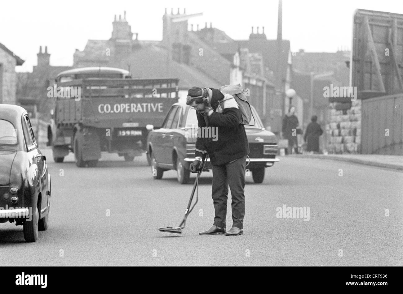 Roger Eyre, Assistant Engineer in training with the Urban District Council, Sutton in Ashfield, Notts, using defunct Mine Detector to locate manhole covers which have been covered by layers of asphalt as road were hurriedly re-surfaced, 26th January 1968. Stock Photo