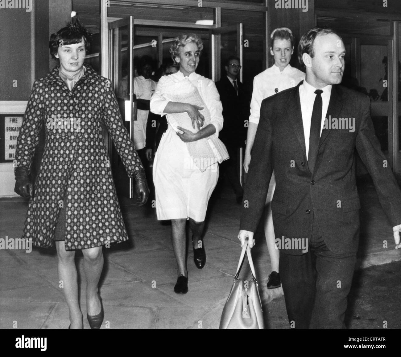 Thorns sextuplets. Julie Thorns, the first of the Thorns sextuplets to leave the Birmingham Maternity Hospital, is carried to the car by Miss Dorothy Hilditch, sister-in-charge of the special care unit, with Mr and Mrs Thorns leading the way. 30th November 1968. Stock Photo