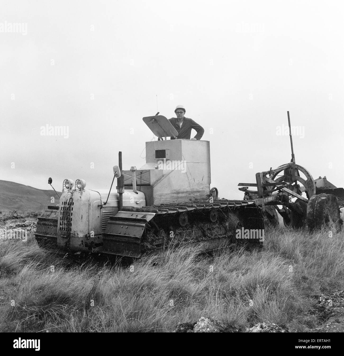 Armoured Tractor, ploughing fields littered with shells and bombs, 31st August 1969. Forestry Commission volunteers help reclaim 900 acres of a Royal Artillery range for forestry work, Trawsfynydd, Merioneth, North Wales. Ploughman John Jones, wearing steel helmet and drives an armoured tractor, one of 12 Forestry Commission volunteers. Stock Photo