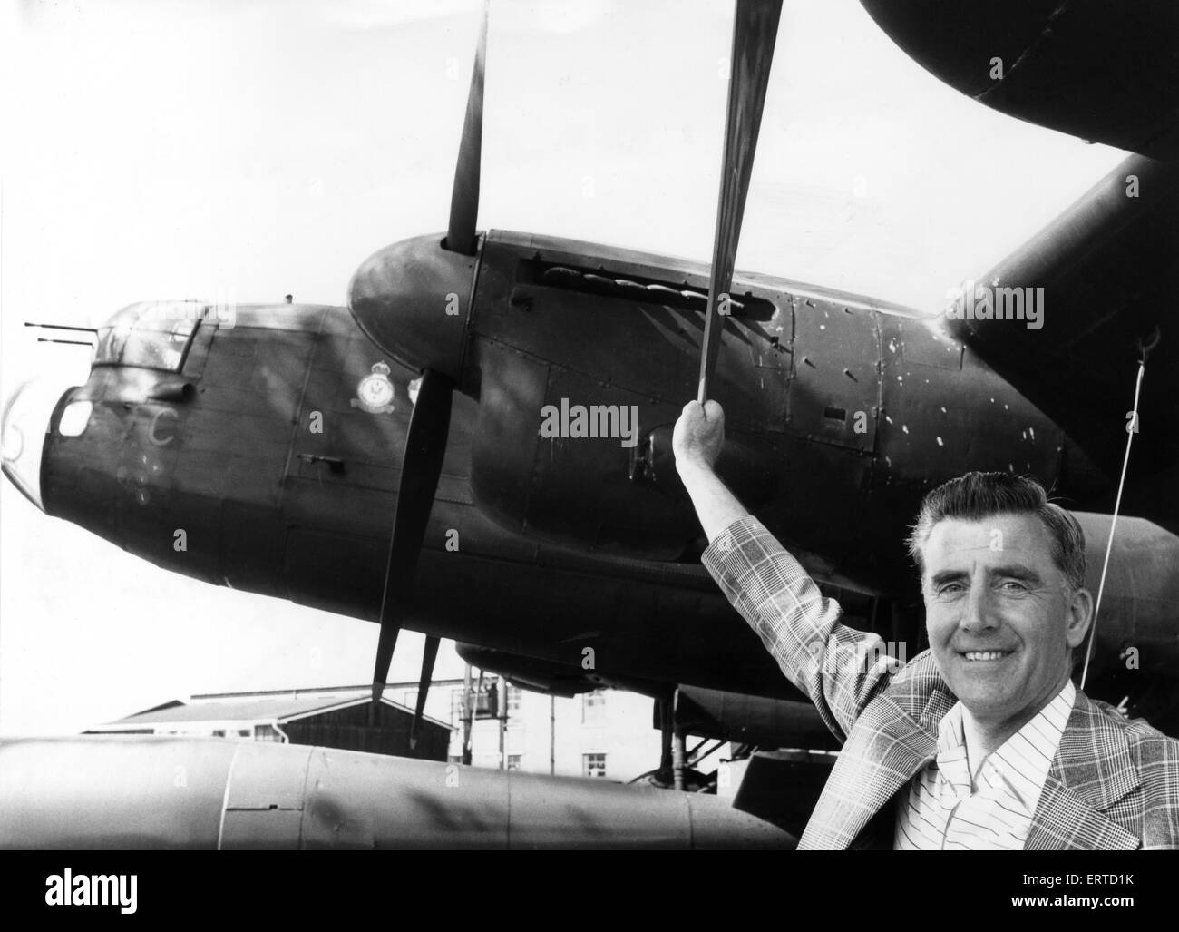 Former RAF flight engineer Alan Morgan in Lancasters, poses beside one of the famous Avro Lancaster bombers at the gate at RAF Scampton. 20th May 1980. Stock Photo