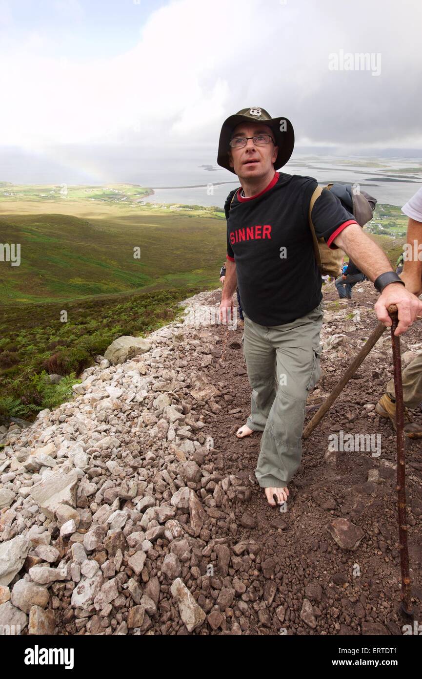 A barefoot man climbing Croagh Patrick a holy mountain in County Mayo
