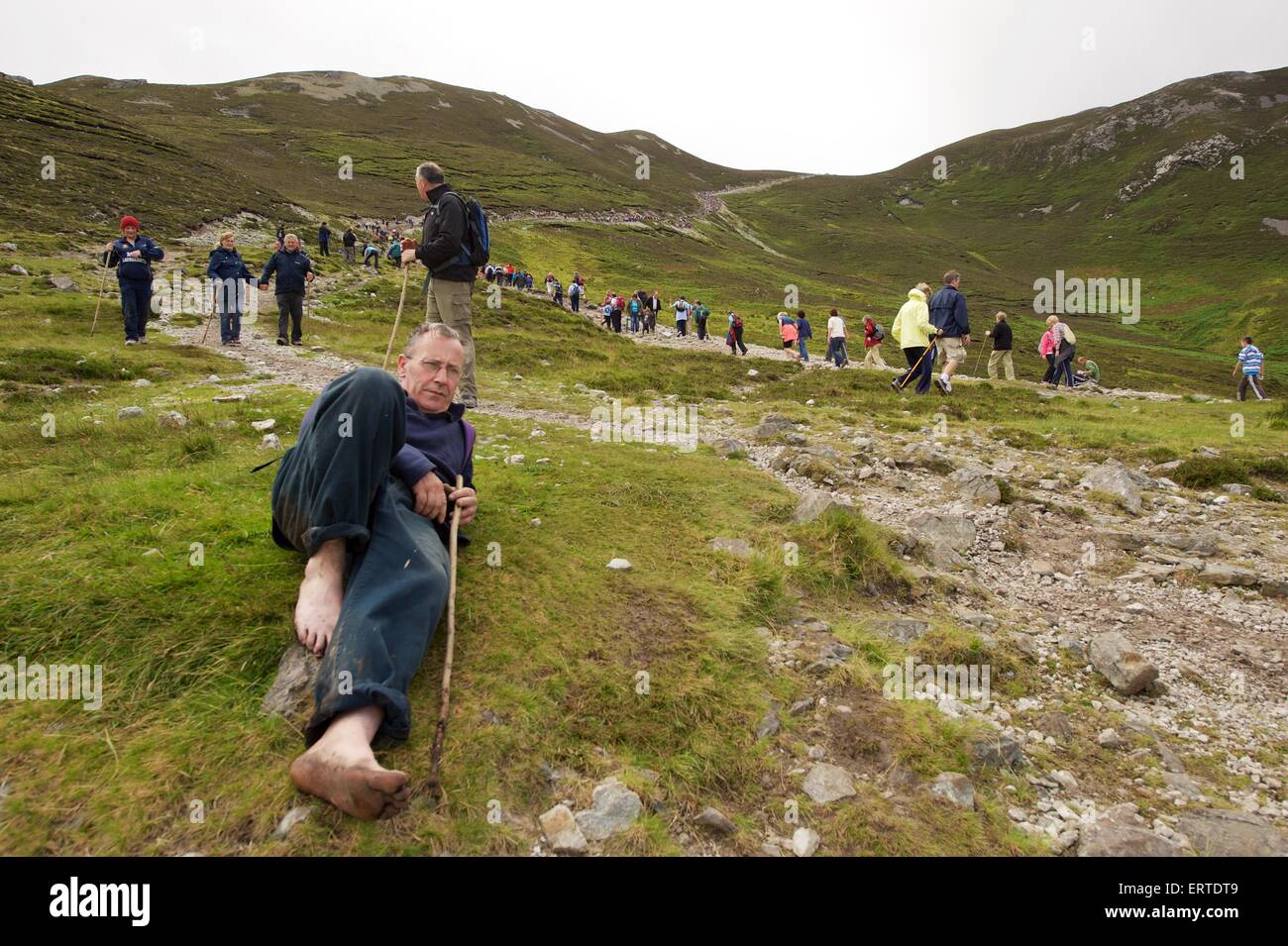 A man in bare feet resting while climbing Croagh Patrick a holy mountain in County Mayo in the