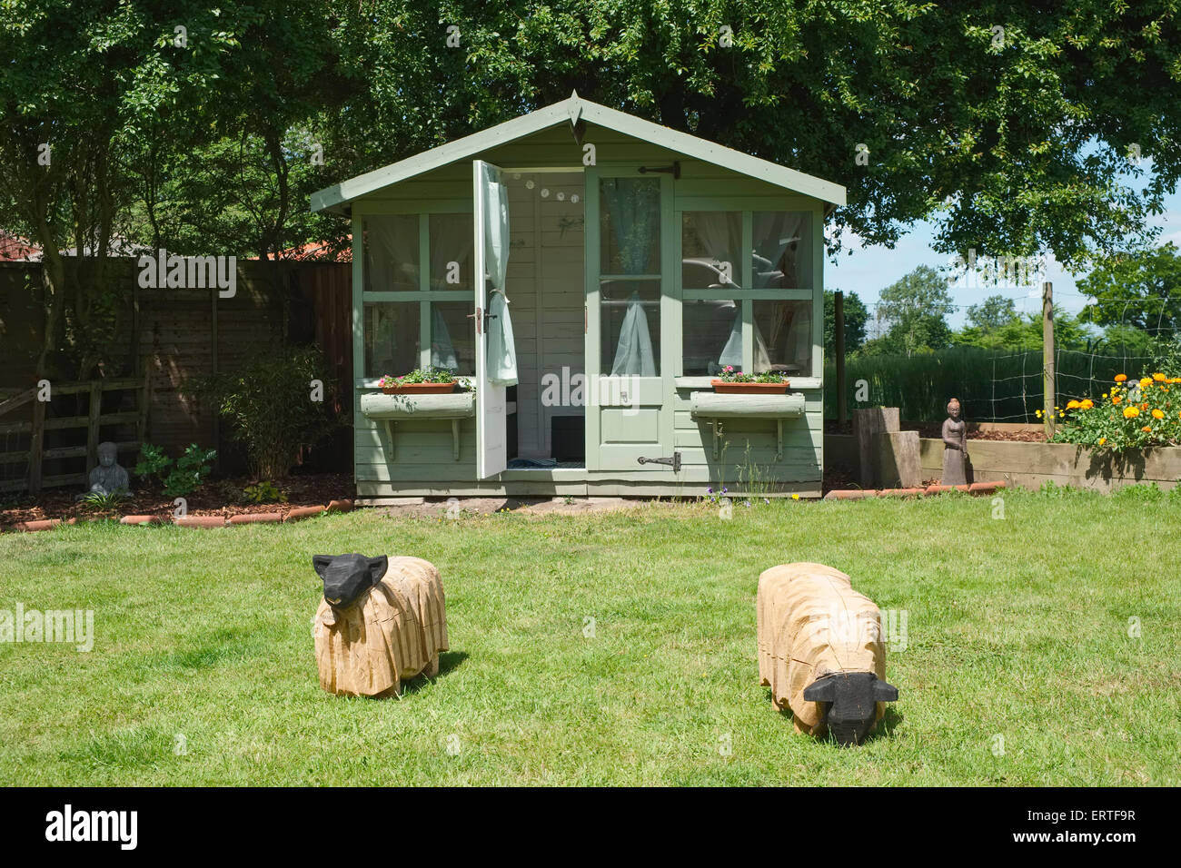 Summer House in Garden with Two Carved Wooden Sheep on Lawn Stock Photo