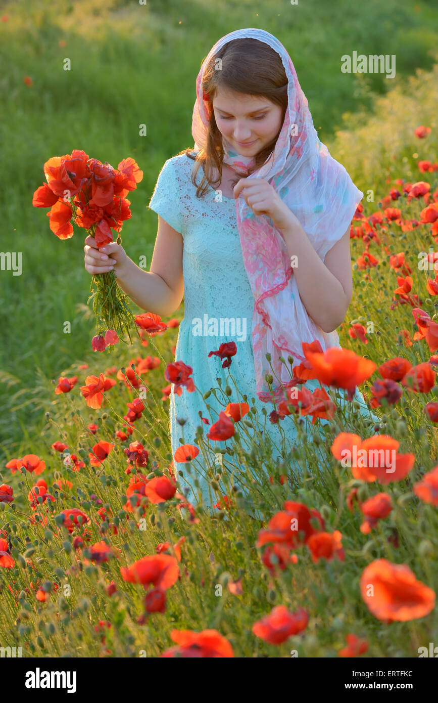 girl  in field of poppies in summer sunset Stock Photo