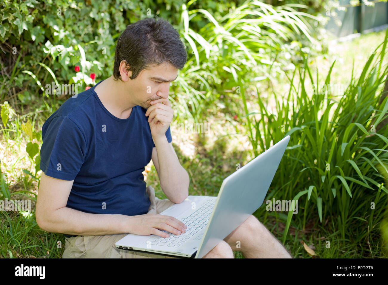 man sitting on the grass working with a laptop Stock Photo - Alamy