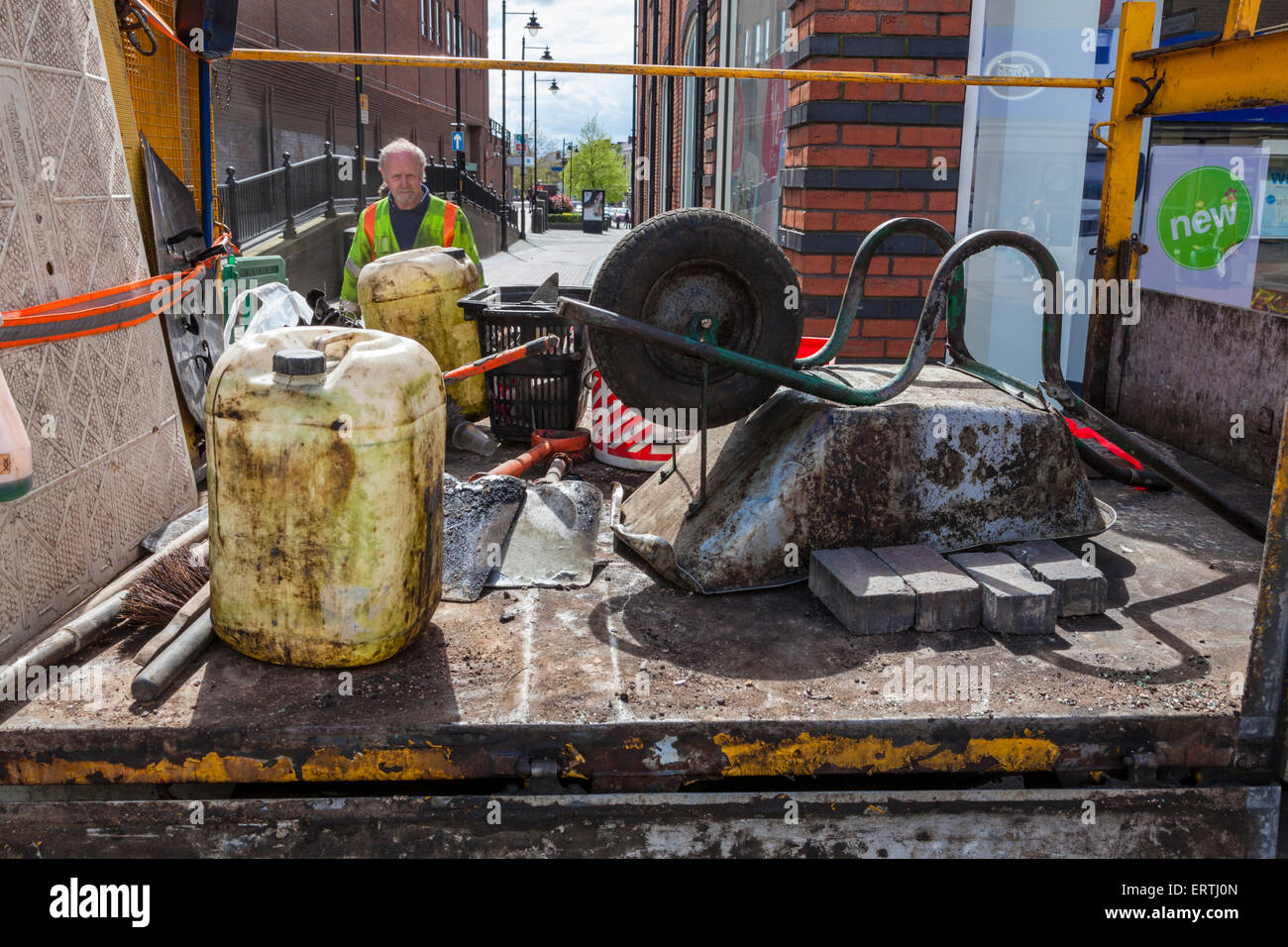 Workman with wheelbarrow and other road maintenance equipment on the ...