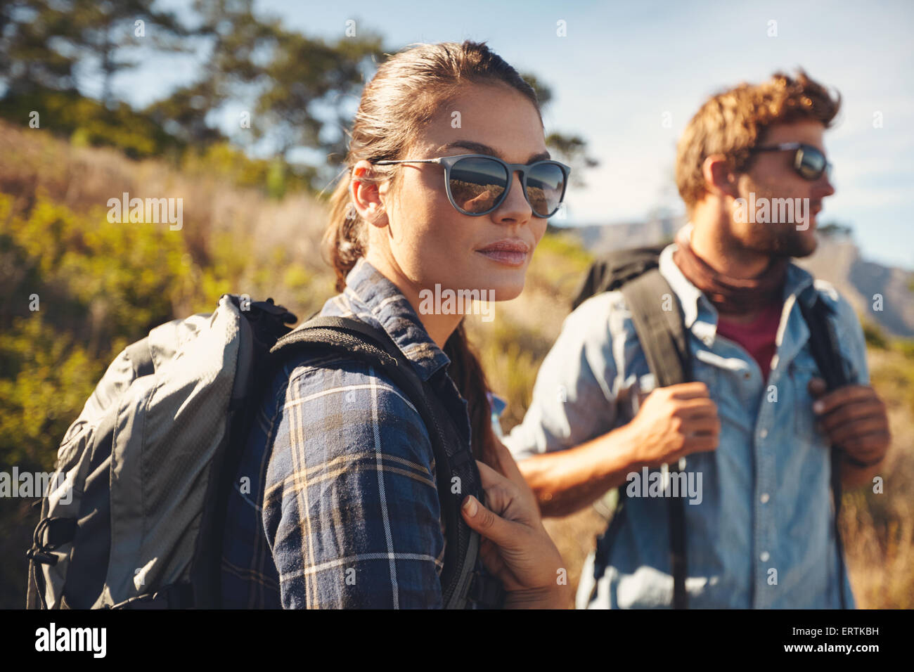 Pretty young woman on a hiking trip with man in the background. Caucasian couple on hike in countryside Stock Photo