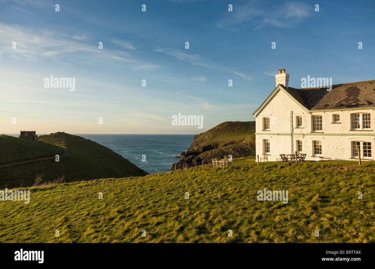 Doyden Castle on headland and house overlook the sea at sunset at Port Quin, Cornwall, England, UK Stock Photo