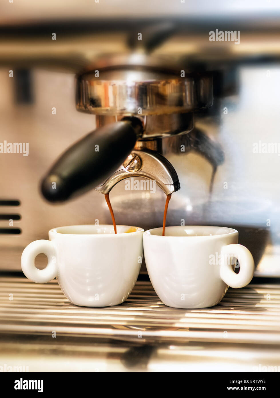 Coffee machine dispensing a double Italian espresso into two small cups Stock Photo