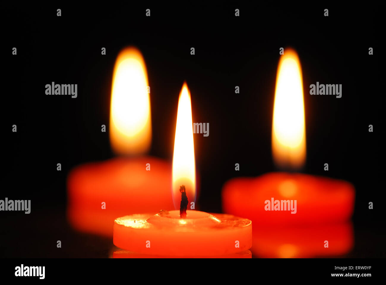 Three burning candles on black background Stock Photo - Alamy
