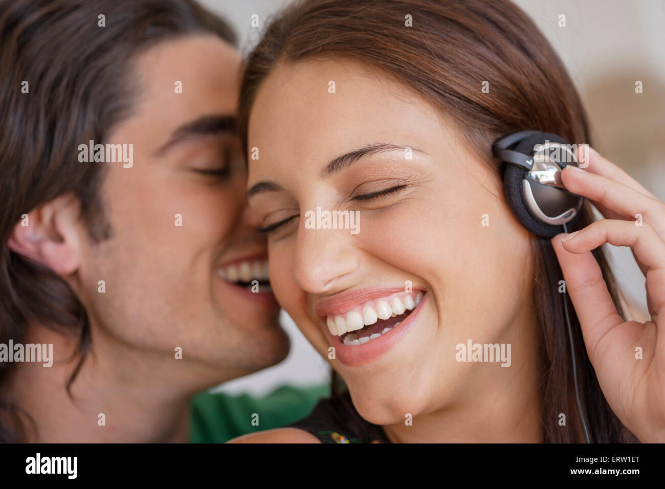 Man whispering woman's ear hires stock