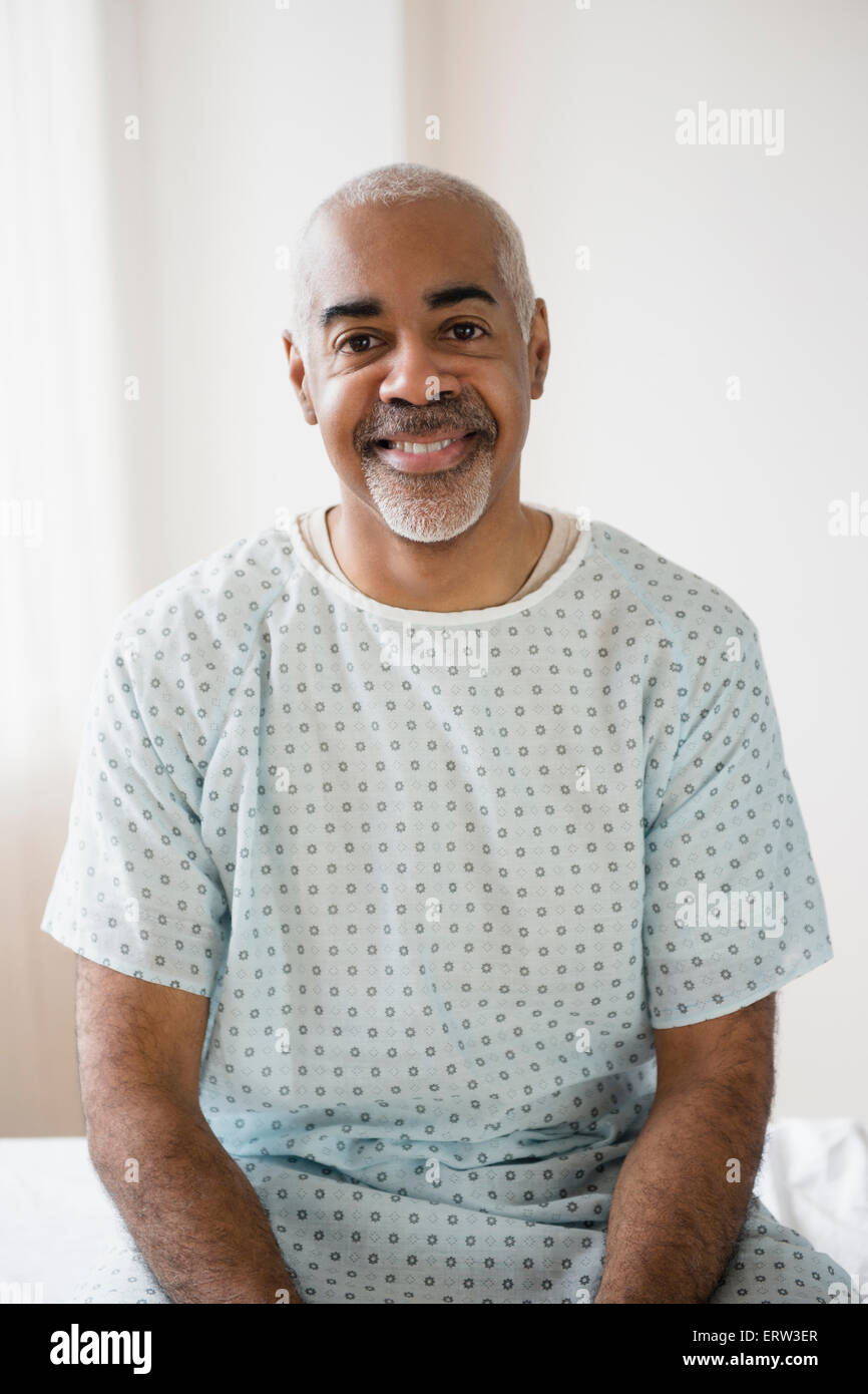 Mixed race older man sitting on hospital bed Stock Photo