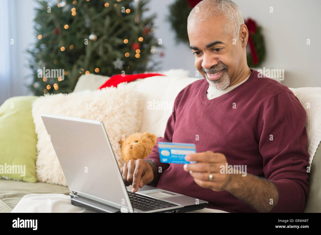 Mixed race man shopping online with laptop at Christmas Stock Photo