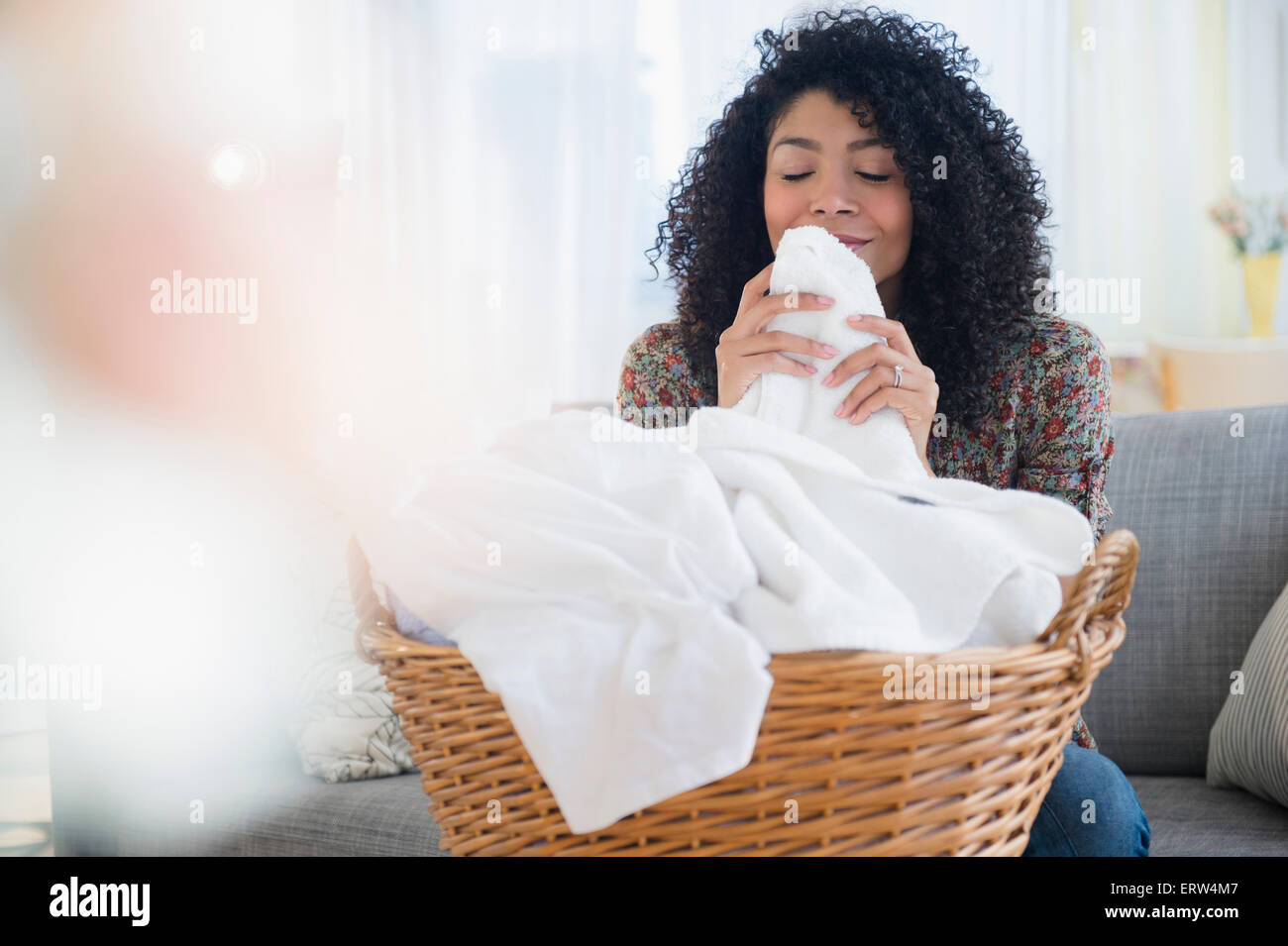 Mixed race woman smelling clean towels in laundry Stock Photo