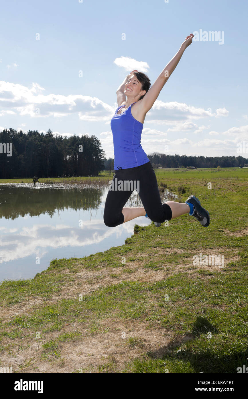 young woman in workout clothes jumping outdoors Stock Photo