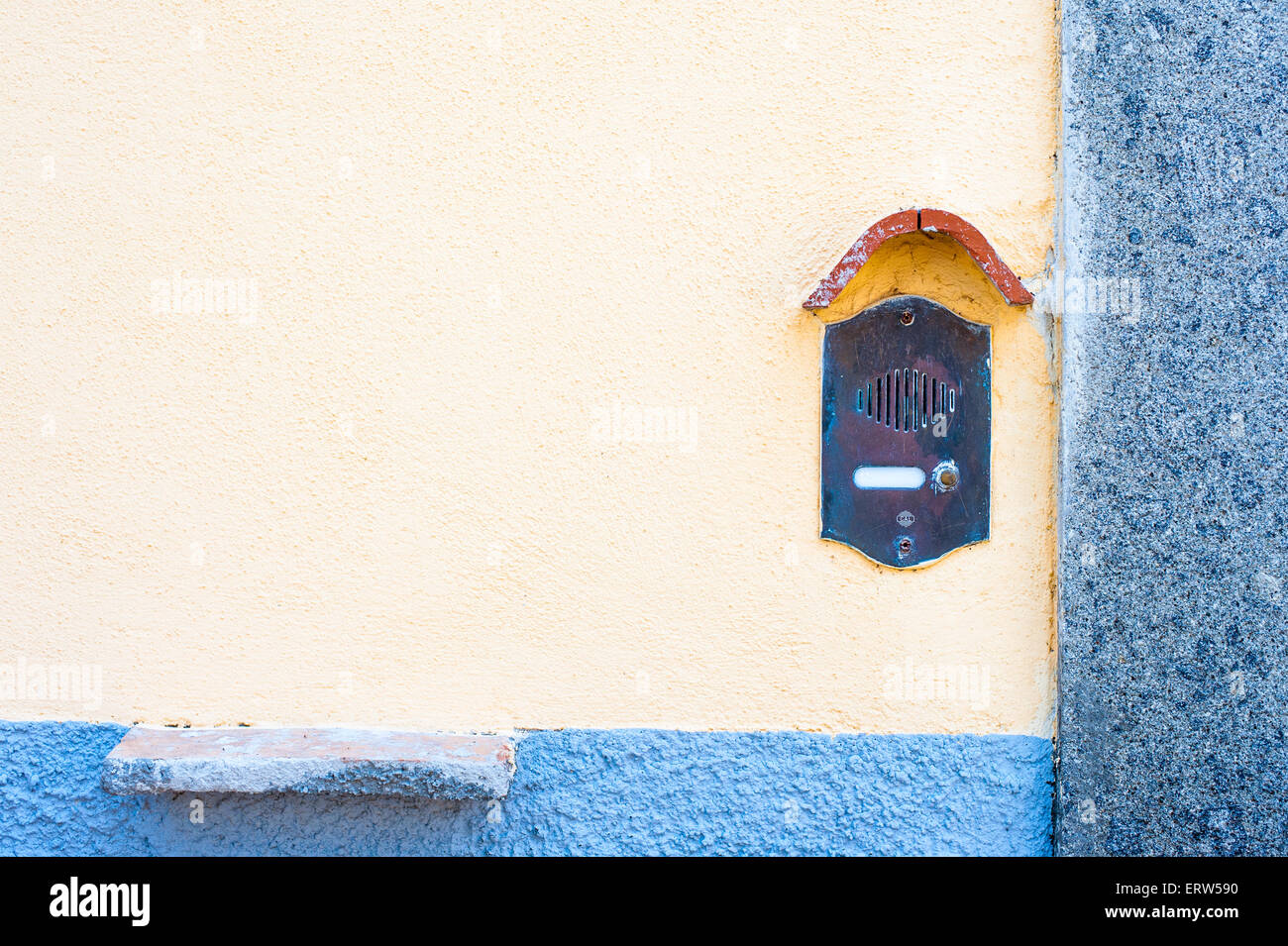 Old fashioned doorbell on orange wall with blue strip and copy space Stock Photo