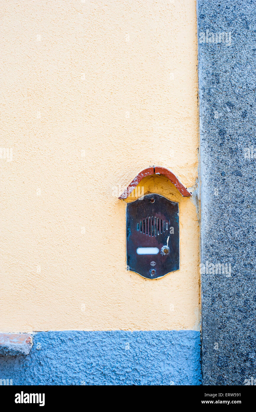 Old fashioned doorbell on orange wall with blue strip and copy space vertical frame Stock Photo