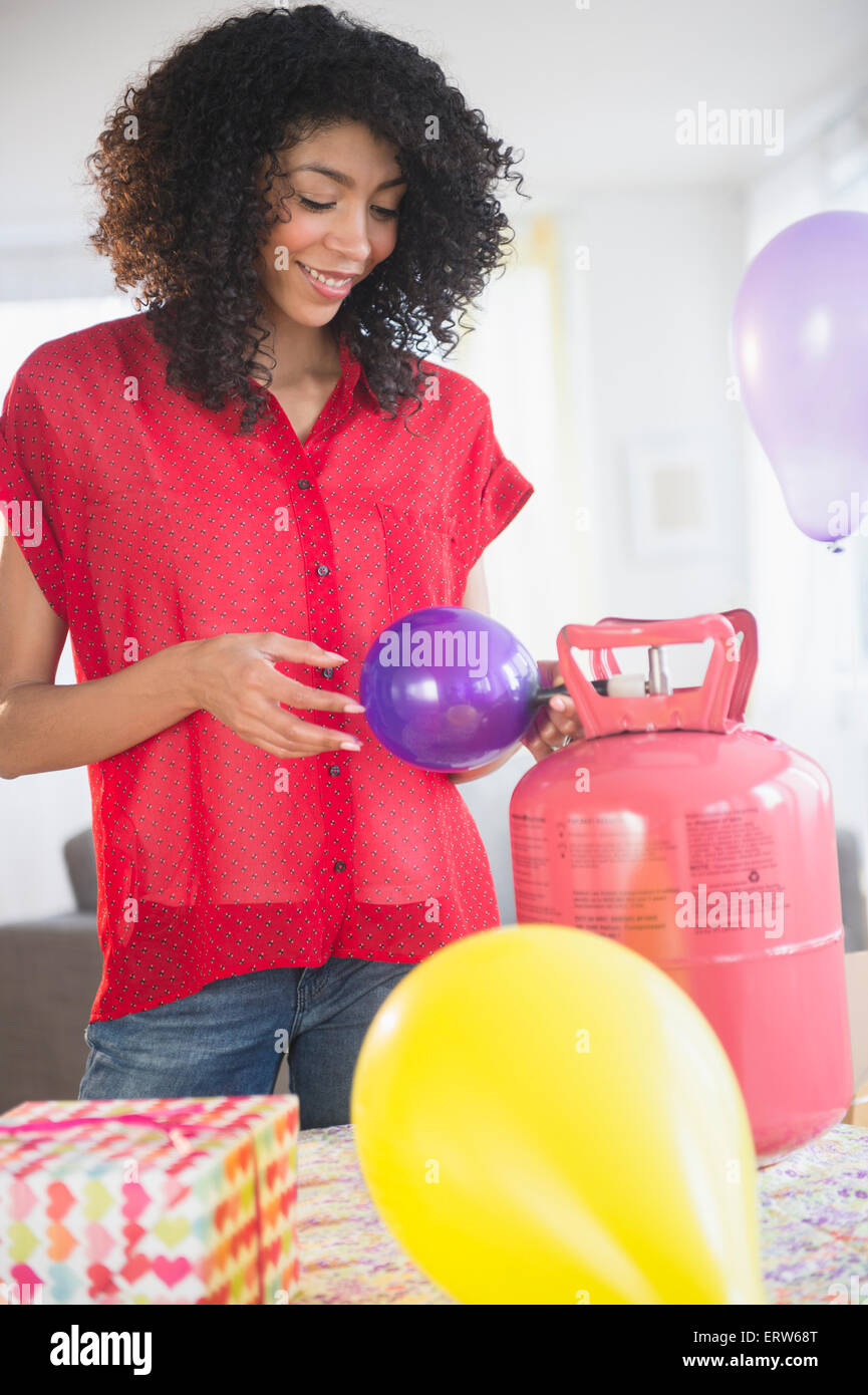 Mixed race woman inflating helium balloons for party Stock Photo Alamy