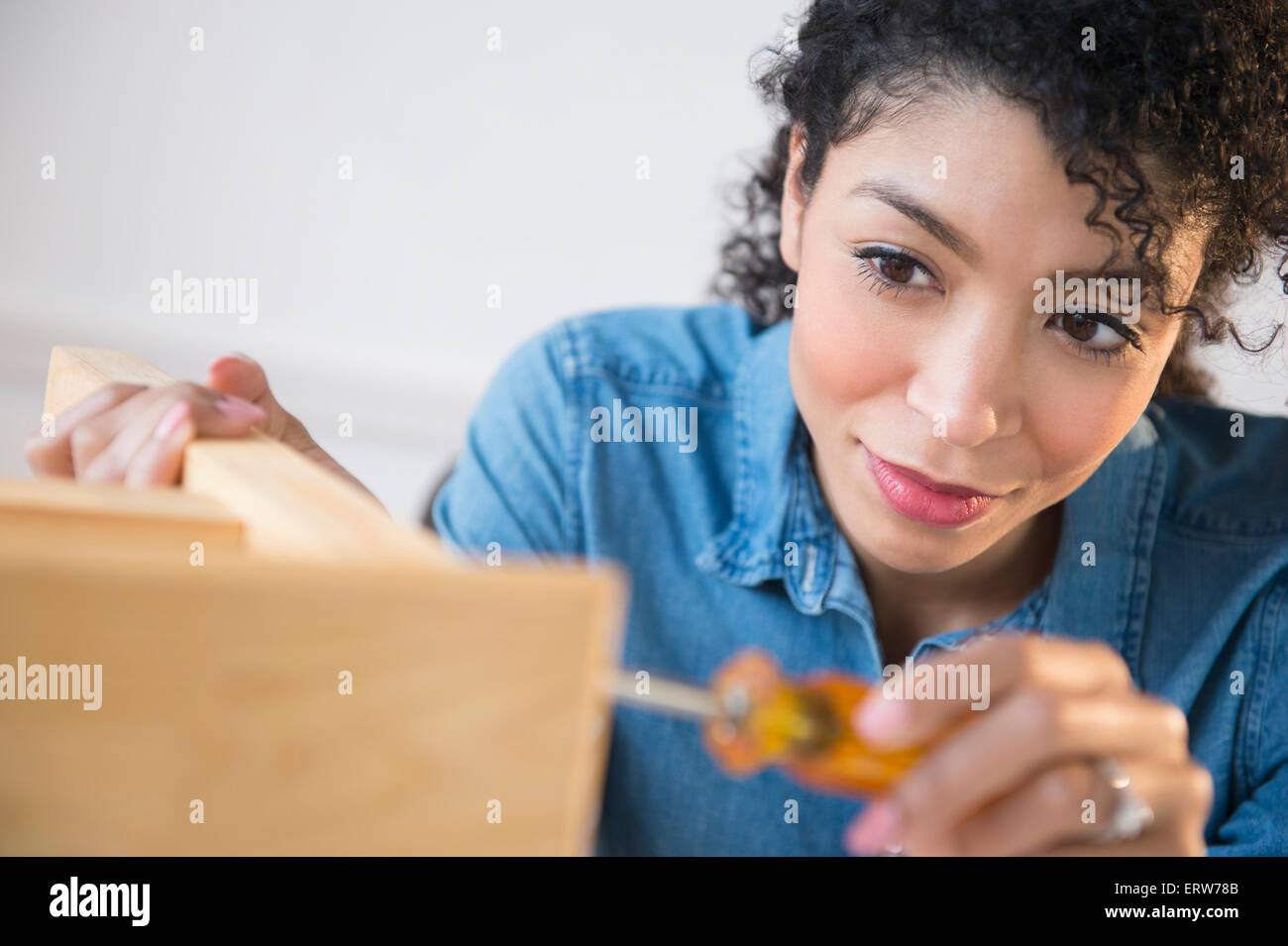 Mixed race woman assembling furniture Stock Photo