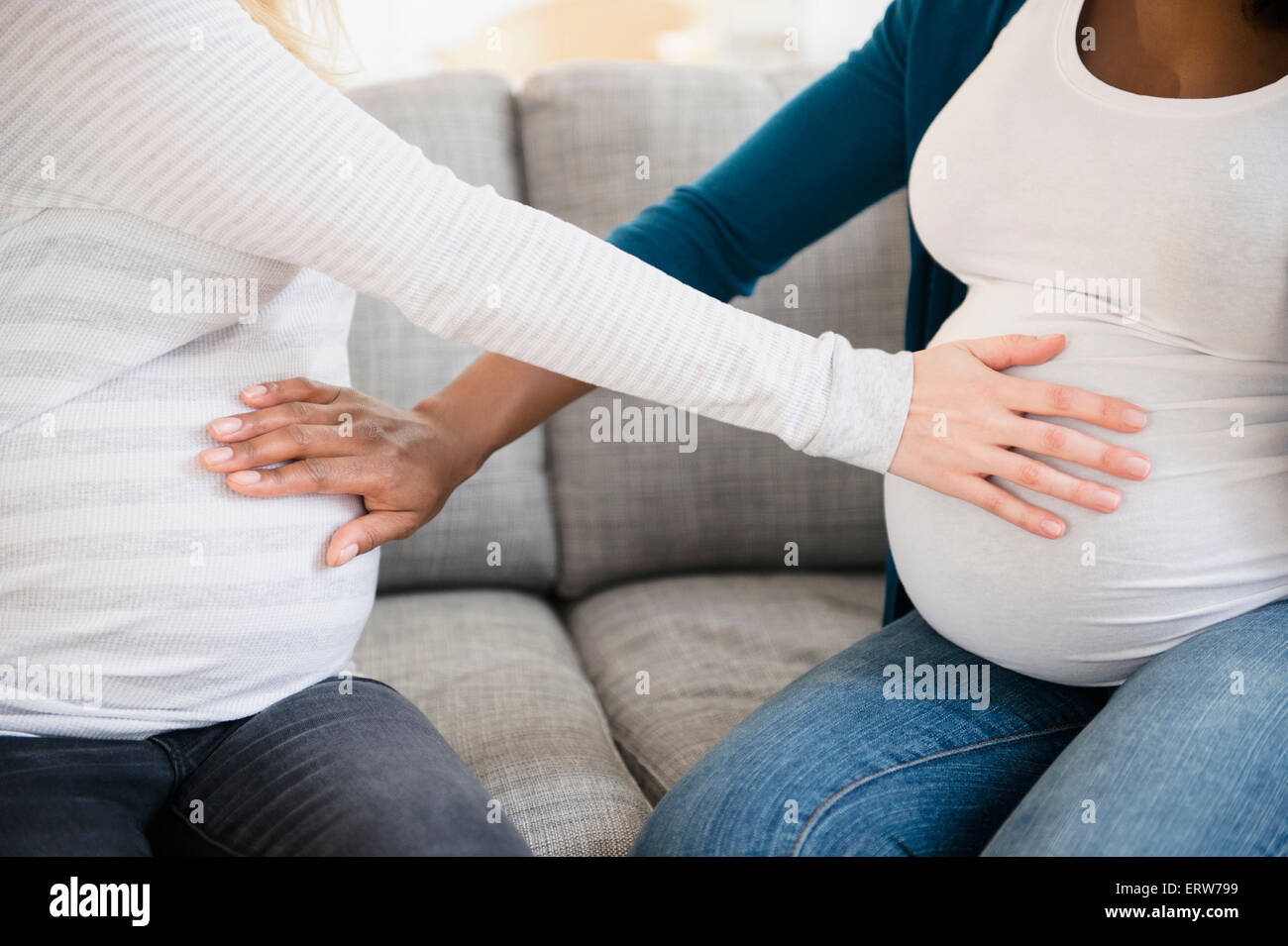 Pregnant women feeling stomachs of each other Stock Photo