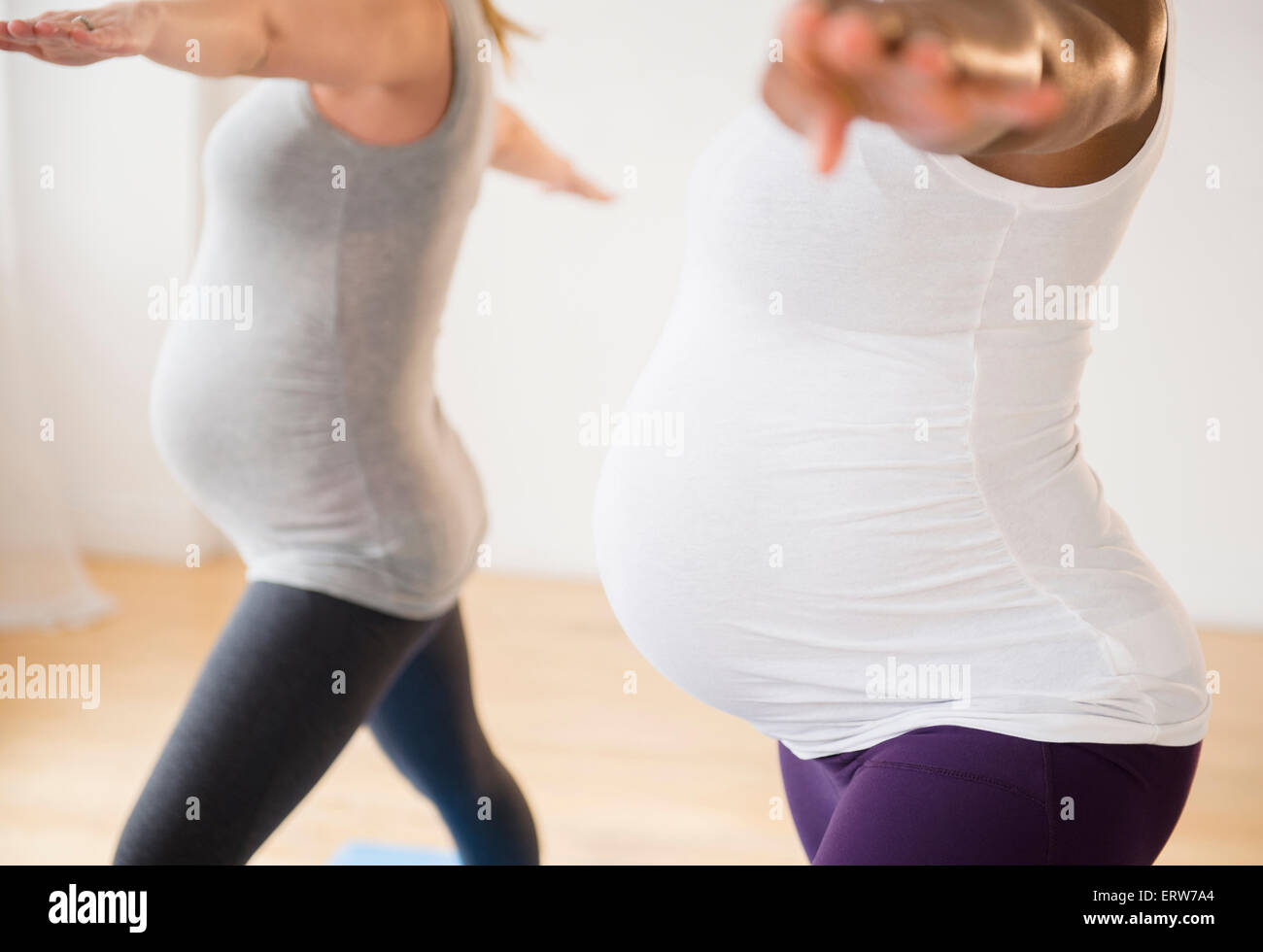Pregnant women practicing yoga with arms outstretched Stock Photo