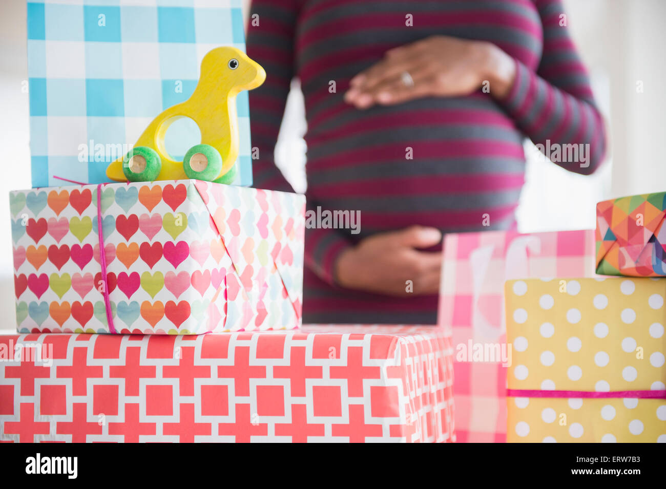 Black pregnant woman admiring gifts at baby shower Stock Photo