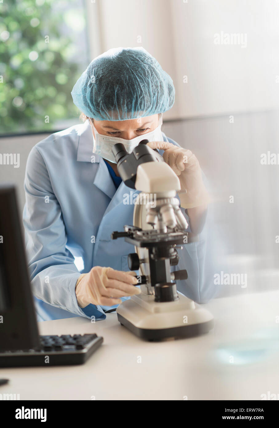 Mixed race scientist using microscope in laboratory Stock Photo