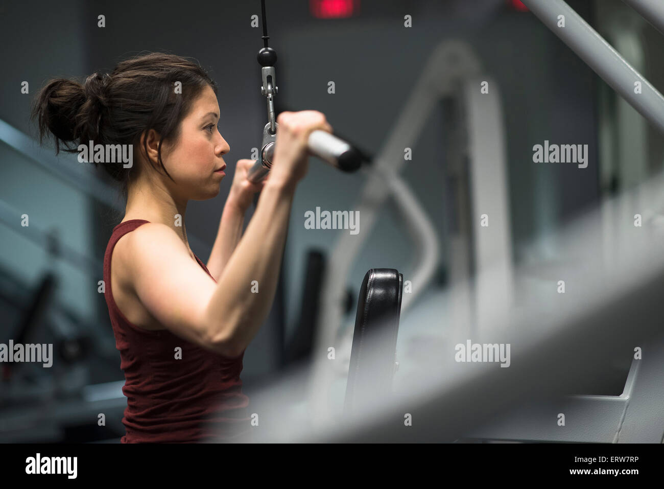 Mixed race woman using exercise machine in gym Stock Photo