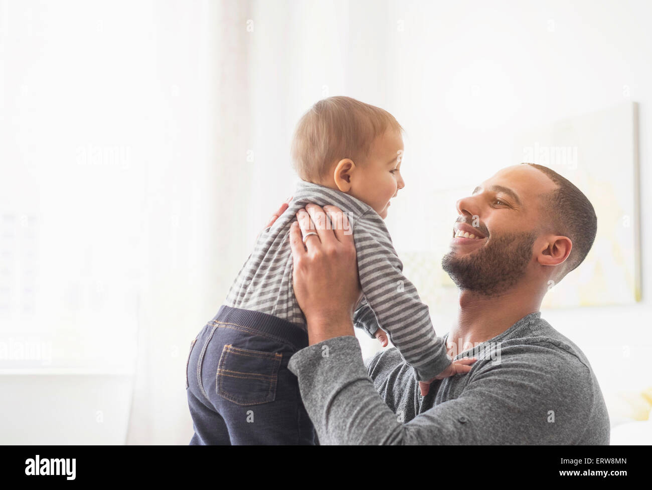 Smiling father holding baby son Stock Photo
