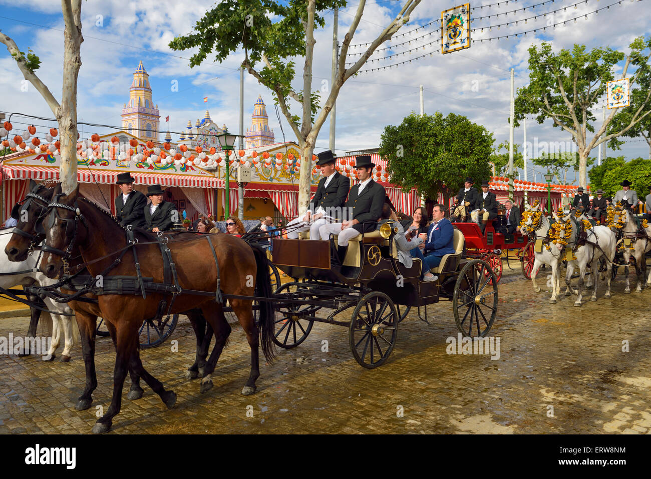 Men dressed in traje corto suits driving teams of horses pulling carriages at Seville April Fair temproary Casetas and Main Gate Stock Photo