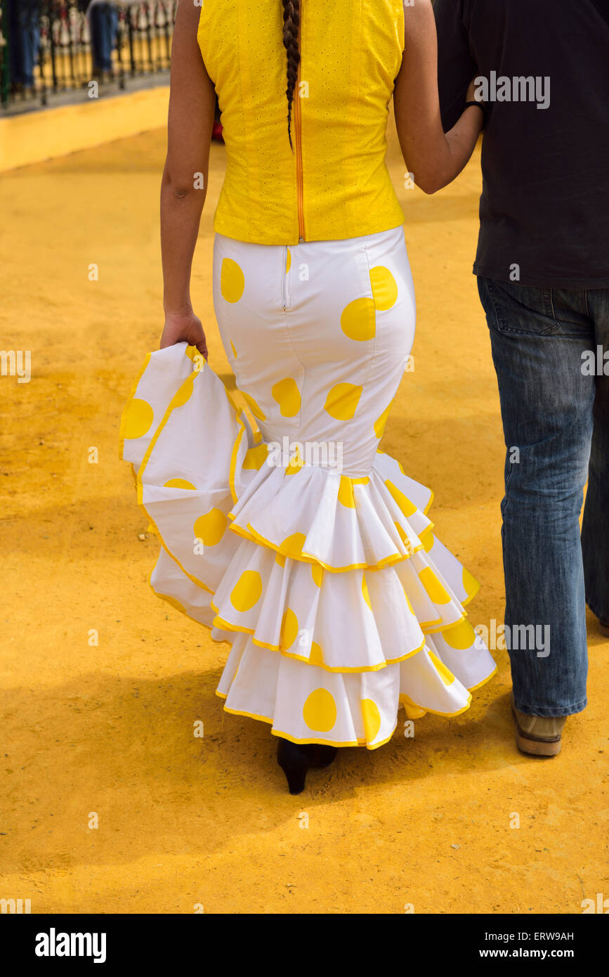 Woman in yellow flamenco dress at the Seville April Fair walking on ochre earth mined in Alcala de Guadaira Stock Photo